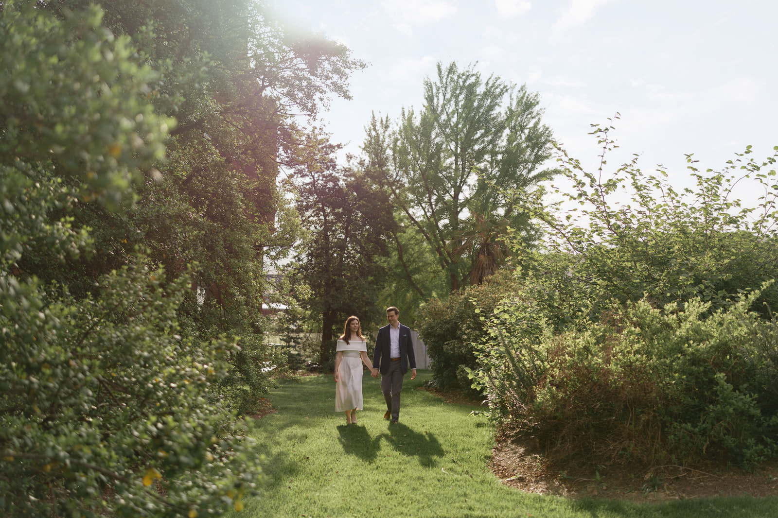Couple embracing beside blooming magnolias during a spring engagement session at the Smithsonian gardens