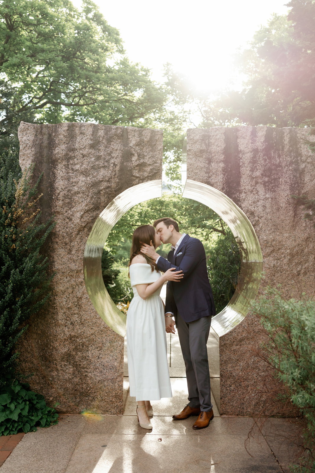 Engaged couple walking through the pink granite moongate at the Enid A. Haupt Garden in DC